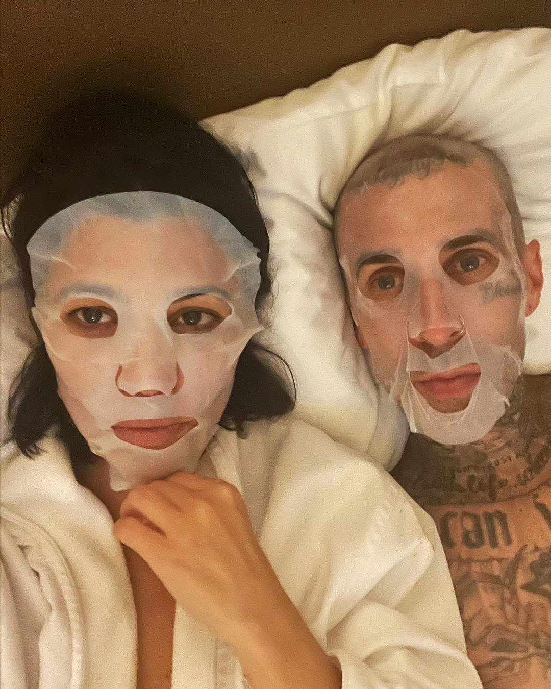 Kourtney Kardashian y Travis Barker posan en la cama con máscaras de sábanas a juego